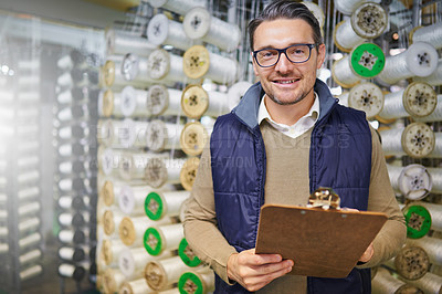 Buy stock photo Portrait of a manager holding a clipboard while standing in front of wire spools on the factory floor