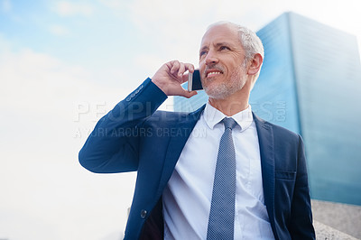 Buy stock photo Shot of a businessman answering his phone while walking to his office in the city