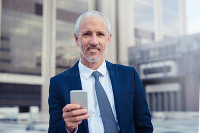Buy stock photo Portrait of a confident businessman using his cellphone while standing outside his office building