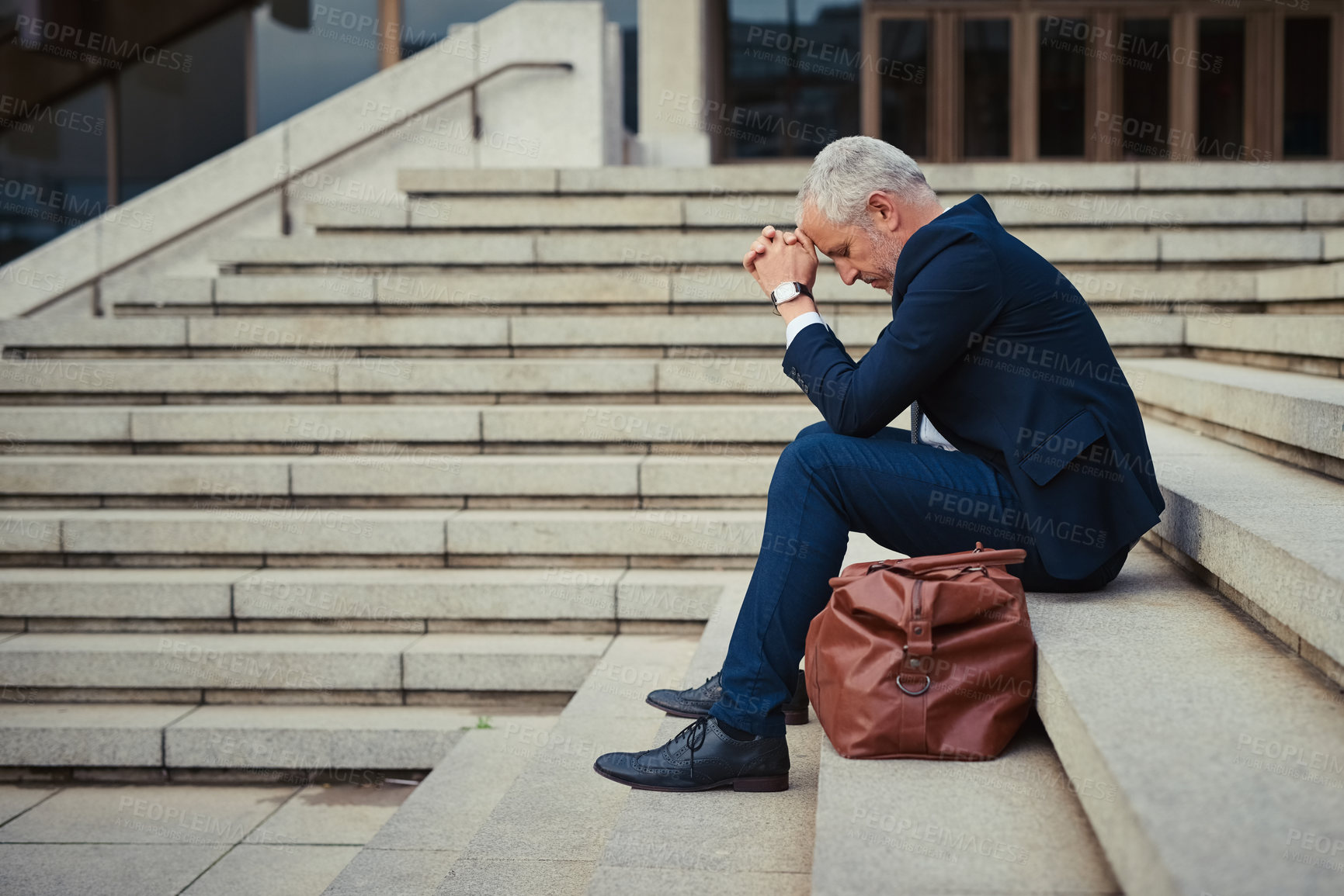 Buy stock photo Shot of a dejected businessman sitting on the stairs outside his office with his head in his hands