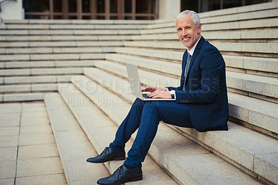 Buy stock photo Portrait of a businessman working on his laptop while sitting on the steps outside his office