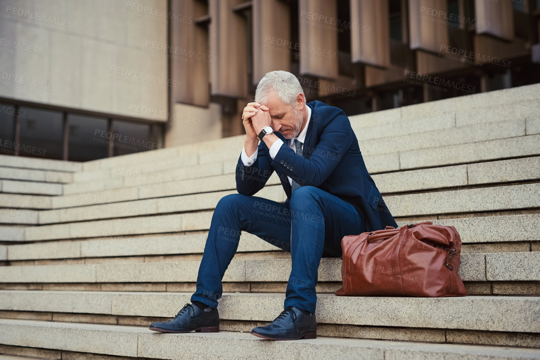 Buy stock photo Shot of a dejected businessman sitting on the stairs outside his office with his head in his hands