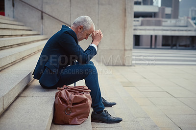 Buy stock photo Shot of a dejected businessman sitting on the stairs outside his office with his head in his hands
