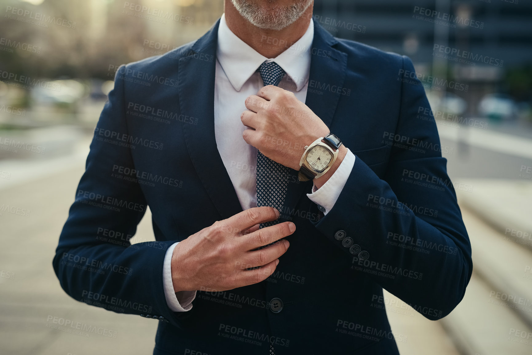 Buy stock photo Cropped shot of an unidentifiable businessman straightening his tie while standing in an urban landscape