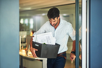 Buy stock photo Shot of a stressed businessman carrying his box of possessions after getting fired from his job