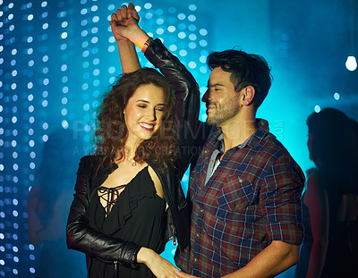 Buy stock photo Shot of an affectionate young couple dancing together in a nightclub