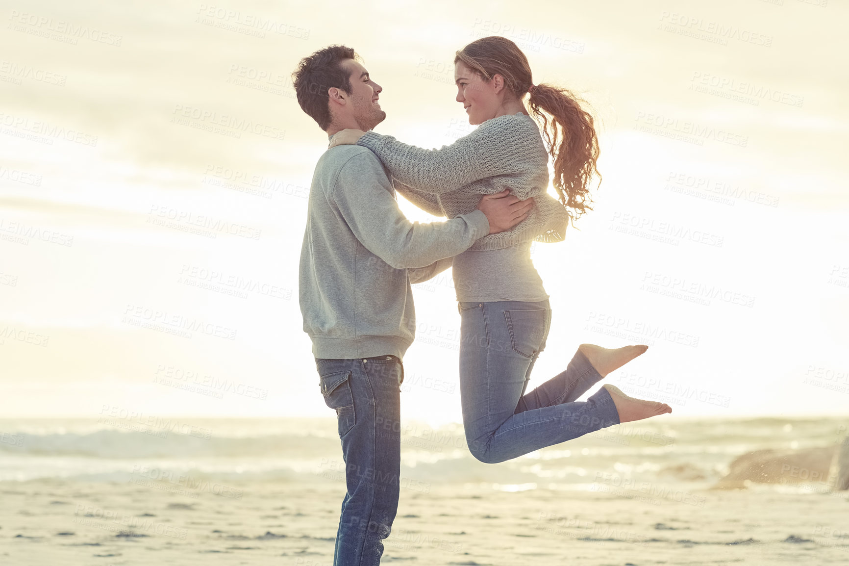 Buy stock photo Shot of a young couple relaxing on the beach together on the weekend