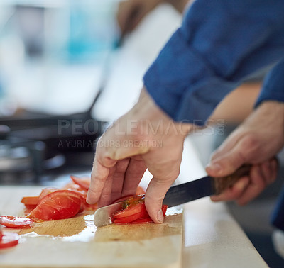 Buy stock photo Shot of an unidentifiable man cutting up tomatoes in his kitchen at home