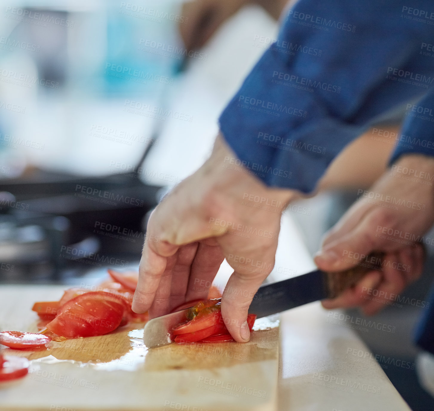 Buy stock photo Shot of an unidentifiable man cutting up tomatoes in his kitchen at home