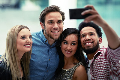 Buy stock photo Shot of a happy group of friends taking a selfie with a smartphone in a nightclub