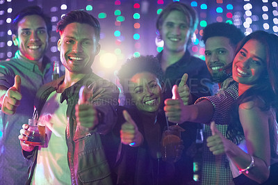 Buy stock photo Portrait of a happy group of friends giving a thumbs up while standing in a nightclub