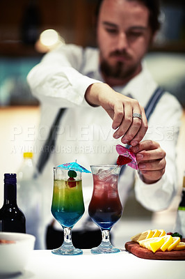 Buy stock photo Shot of a skilled barman garnishing a cocktail in a bar