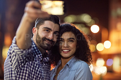 Buy stock photo Shot of an affectionate young couple taking a selfie while out on a date in the city