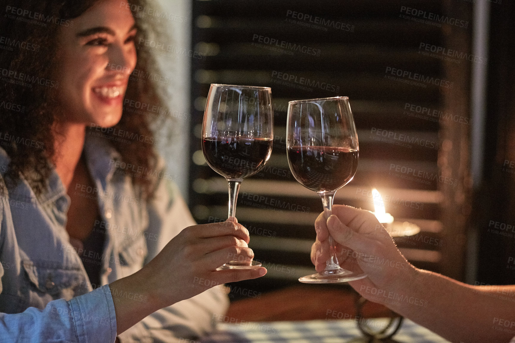 Buy stock photo Shot of a happy young couple clinking their glasses while enjoying a dinner date