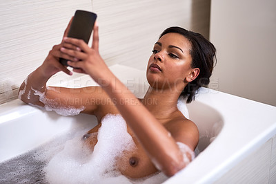 Buy stock photo Shot of an attractive young woman taking a selfe while relaxing in a bubble bath