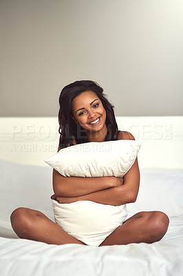 Buy stock photo Portrait of an attractive young woman in hugging her pillow while sitting on her bed