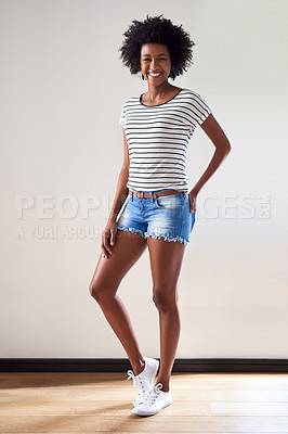 Buy stock photo Portrait of an attractive and happy young woman wearing a striped sweater and denim shorts indoors