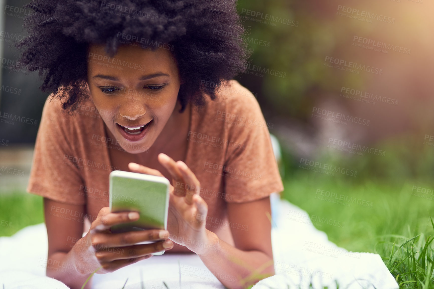 Buy stock photo Shot of a young man texting while relaxing at the park