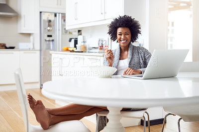 Buy stock photo Shot of a young woman surfing the net while enjoying breakfast in her kitchen at home