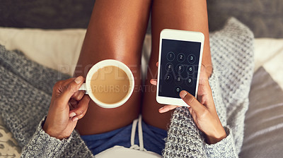 Buy stock photo Shot of an unidentifiable young woman using her cellphone while enjoying a cup of coffee at home