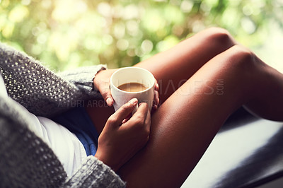 Buy stock photo Shot of an unidentifiable young woman enjoying a cup of coffee while sitting by a window at home
