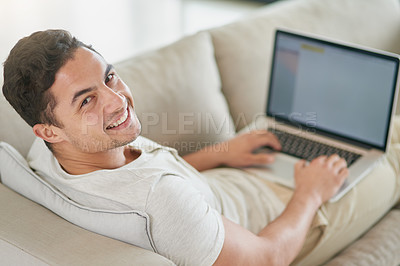 Buy stock photo Laptop, sofa and portrait of man doing remote work in his home, house or apartment with smile and relax in living room. Couch, happy and young male person or freelancer typing a project online or web