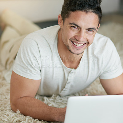 Buy stock photo Laptop, relax and portrait of man typing on the floor in his home, house or apartment with smile lying on carpet. ecommerce, happy and young male person or freelancer doing remote work or project