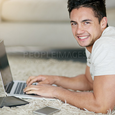 Buy stock photo Laptop, blogging and portrait of man typing as remote work in his home, house or apartment with smile on the floor. Carpet, happy and young male person or freelancer working on project online or web