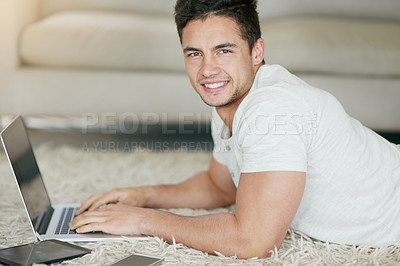 Buy stock photo Portrait of a relaxed young man using a laptop on the floor at home