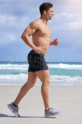 Buy stock photo Shot of a handsome young man jogging on the beach