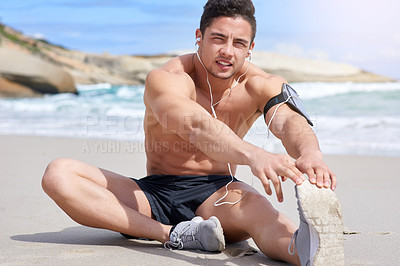 Buy stock photo Portrait of a handsome young man stretching before his run on the beach