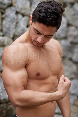 Buy stock photo Shot of a handsome young man flexing outside