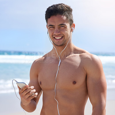 Buy stock photo Portrait of a handsome young man setting up his workout playlist on the beach