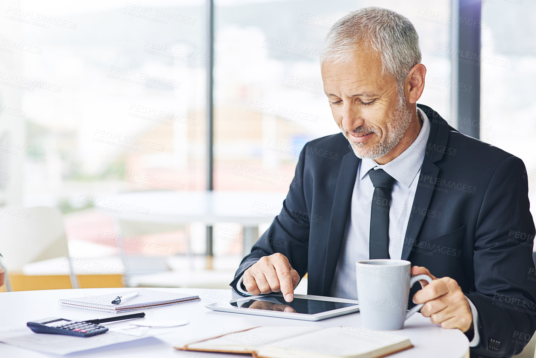 Buy stock photo Cropped shot of a mature businessman working on a digital tablet in an office