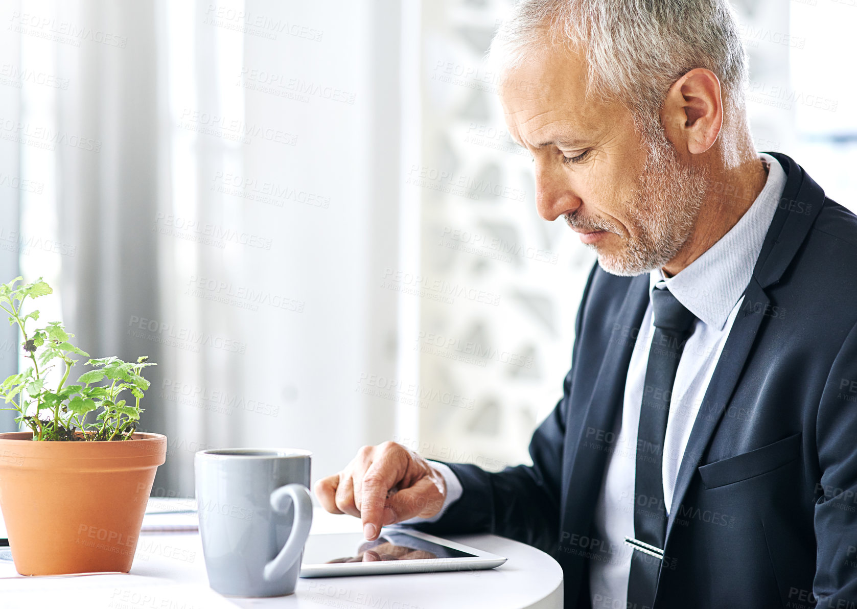 Buy stock photo Cropped shot of a mature businessman working on a digital tablet in an office