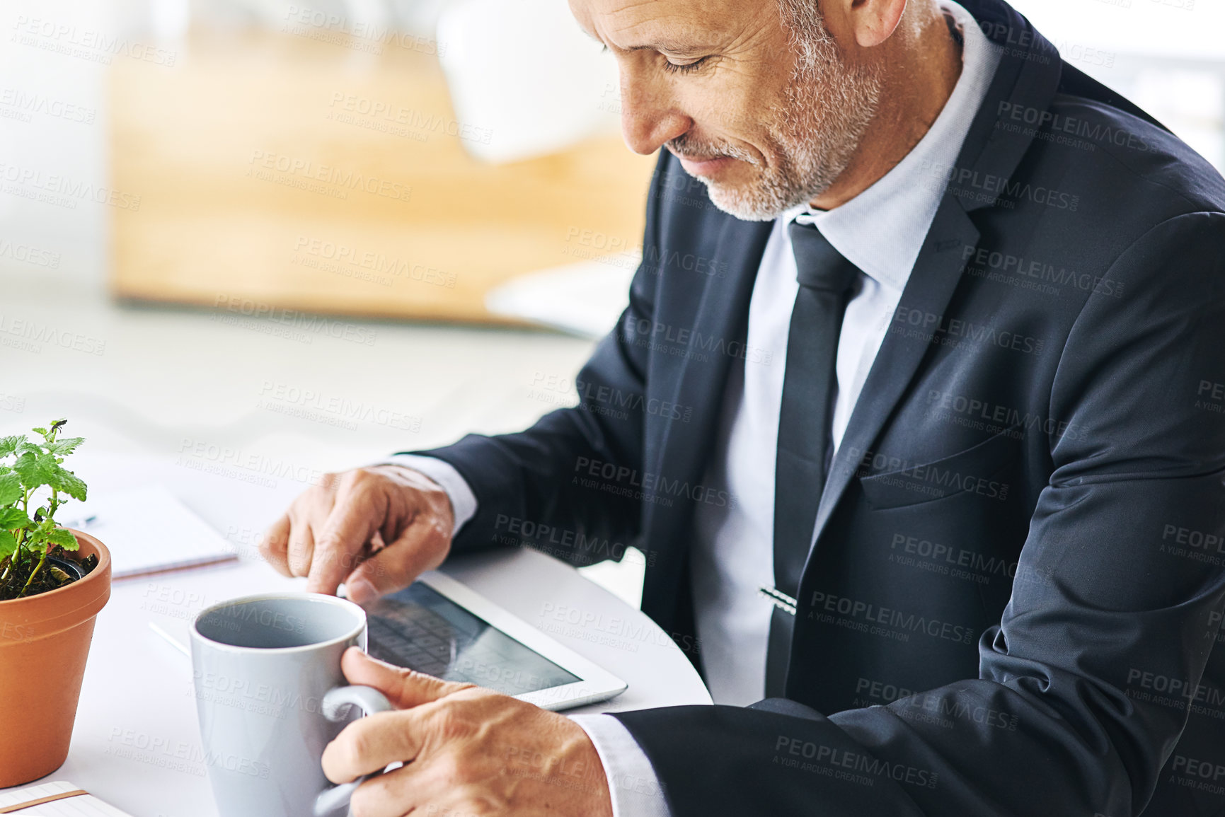 Buy stock photo Cropped shot of a mature businessman working on a digital tablet in an office