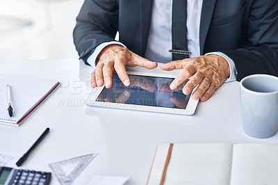 Buy stock photo Cropped shot of a corporate businessman working on a digital tablet in an office