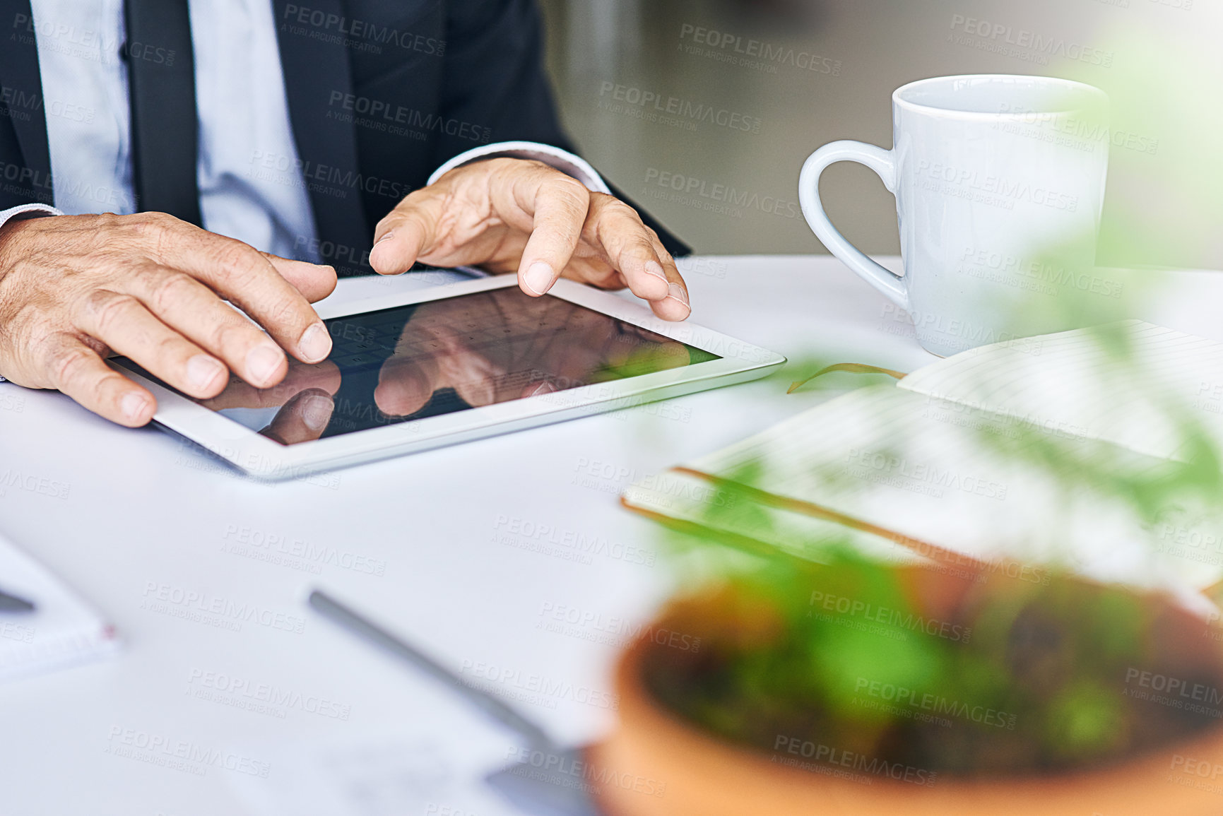 Buy stock photo Cropped shot of a corporate businessman working on a digital tablet in an office