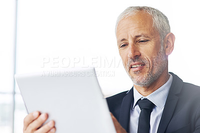 Buy stock photo Cropped shot of a mature businessman working on a digital tablet in an office