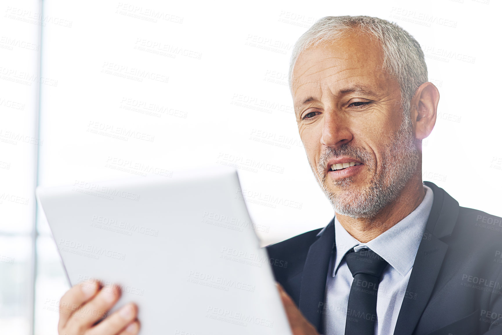 Buy stock photo Cropped shot of a mature businessman working on a digital tablet in an office