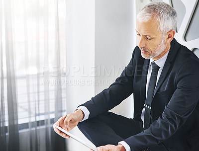 Buy stock photo Cropped shot of a mature businessman working on a digital tablet in an office
