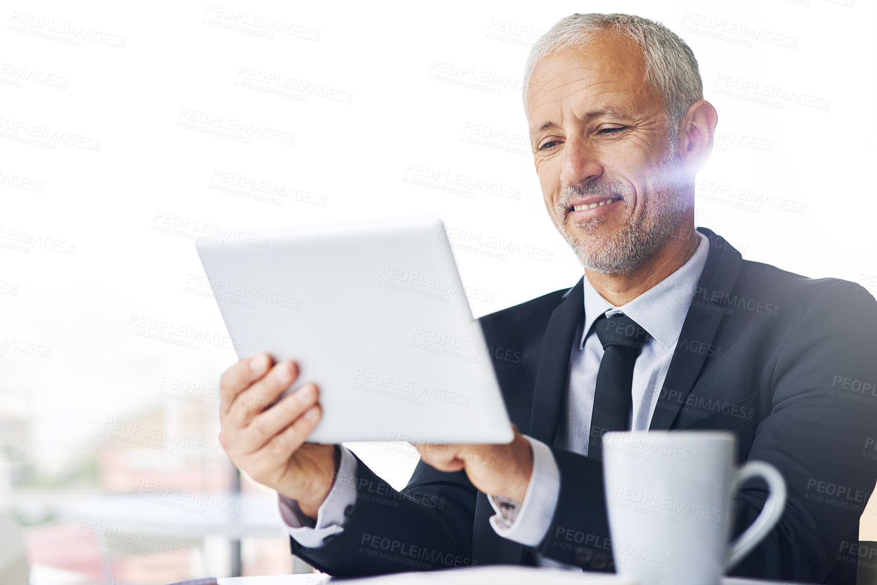 Buy stock photo Cropped shot of a mature businessman working on a digital tablet in an office