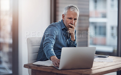 Buy stock photo Cropped shot of a thoughtful mature businessman working on a laptop in an office