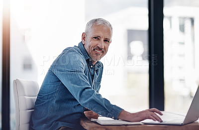 Buy stock photo Portrait of a mature businessman working on a laptop in an office