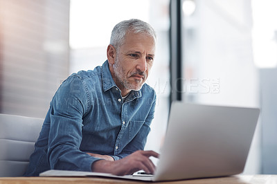 Buy stock photo Cropped shot of a mature businessman working on a laptop in an office