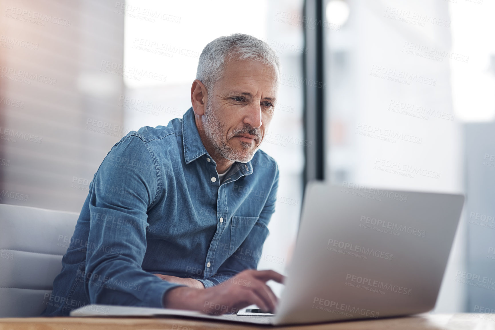 Buy stock photo Cropped shot of a mature businessman working on a laptop in an office