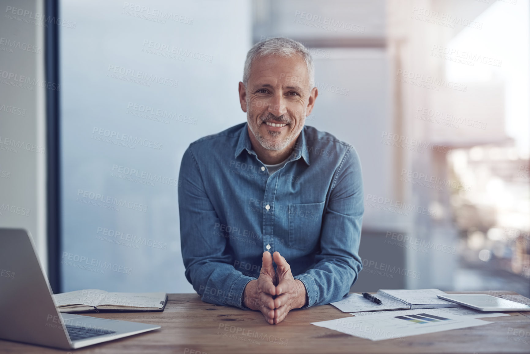 Buy stock photo Portrait, business and mature man at desk, laptop and smile with hands together. Face, employee and professional in modern office, computer and happiness with confidence, pride and sales researcher