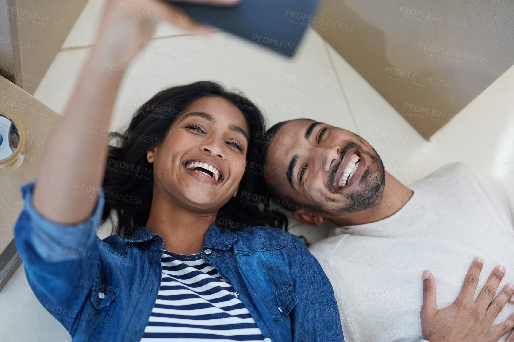 Buy stock photo Shot of a happy young couple taking a selfie while moving into their new house together