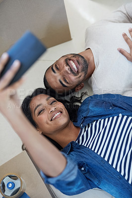 Buy stock photo Shot of a happy young couple taking a selfie while moving into their new house together