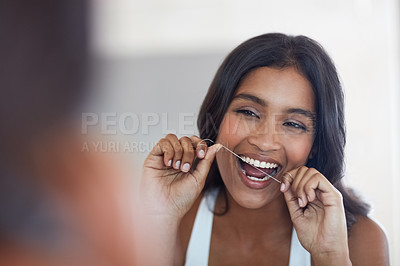 Buy stock photo Shot of an attractive and happy young woman flossing her teeth in the bathroom at home